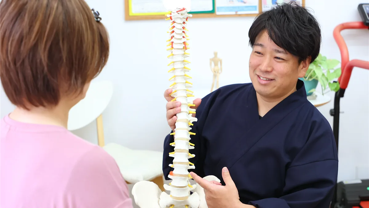背骨の模型を使って状態を説明する院長